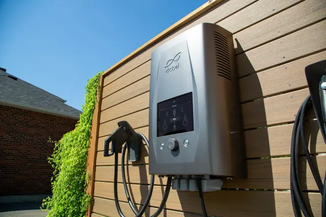 A home EV charger mounted on a wooden fence