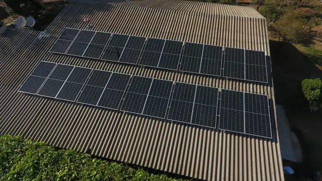 Two rows of solar panels on a corrugated house roof, seen from above